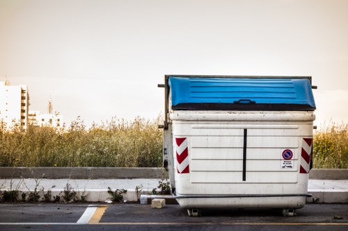 Front view of skip and delivery vehicle at depot